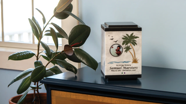 white marble urn with palm tree design sits on a table