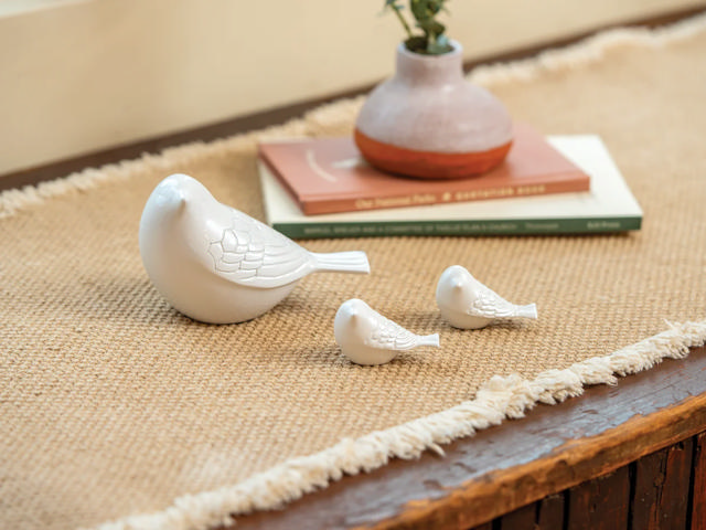 three white bird figurines sit on a table