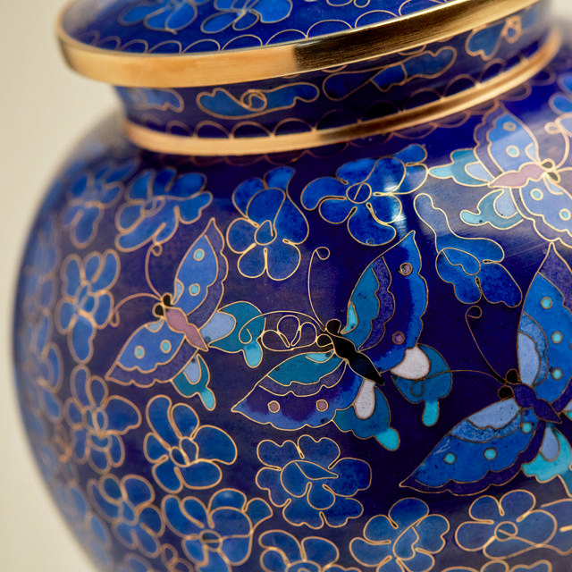 Close up photo of a blue urn decorated with butterflies